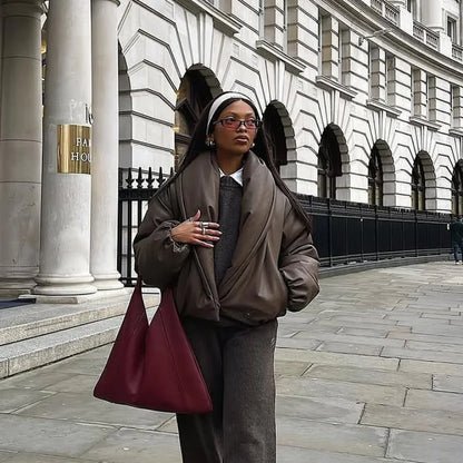 Person in formal attire with a red bag standing in front of a classical building.