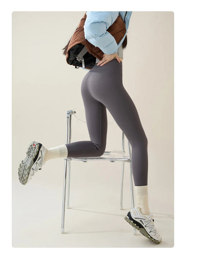 Person wearing gray leggings sitting on a chair with a neutral background