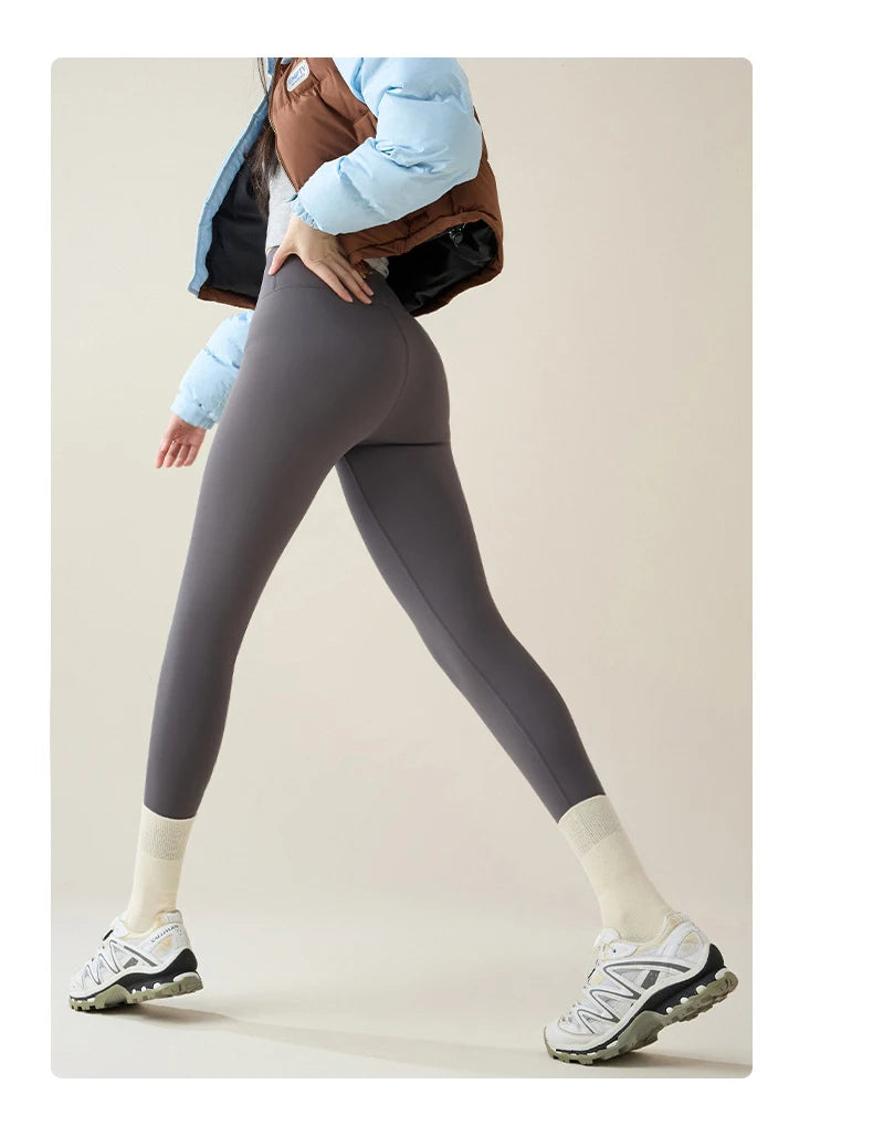 Person wearing gray leggings and a light blue jacket on a beige background