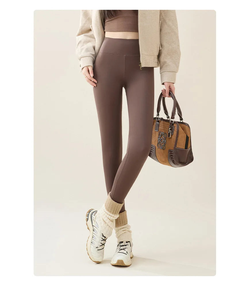Person wearing brown leggings holding a brown handbag on a beige background
