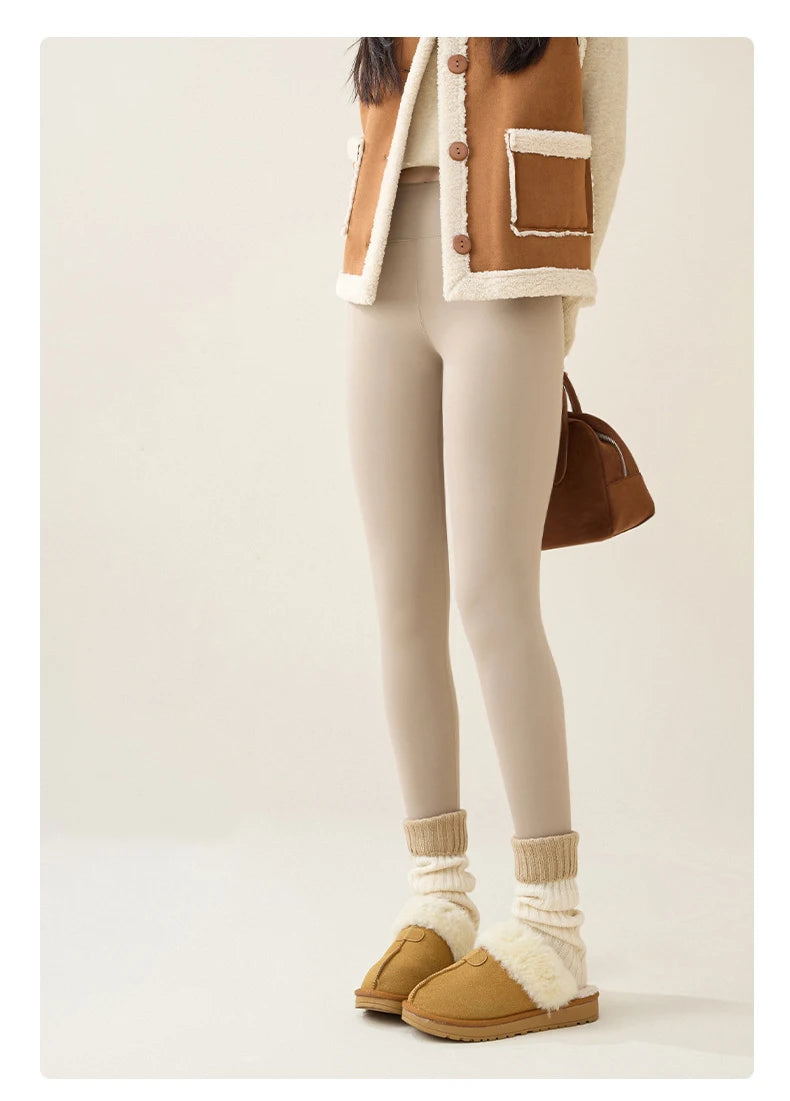 Person wearing a brown and beige jacket, white leggings, and tan shoes on a plain background