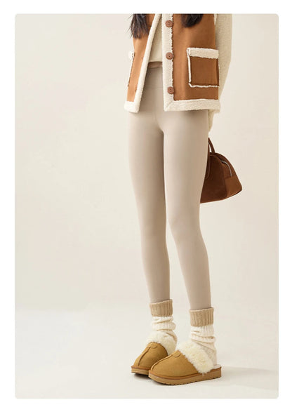 Person wearing a brown and beige jacket, white leggings, and tan shoes on a plain background