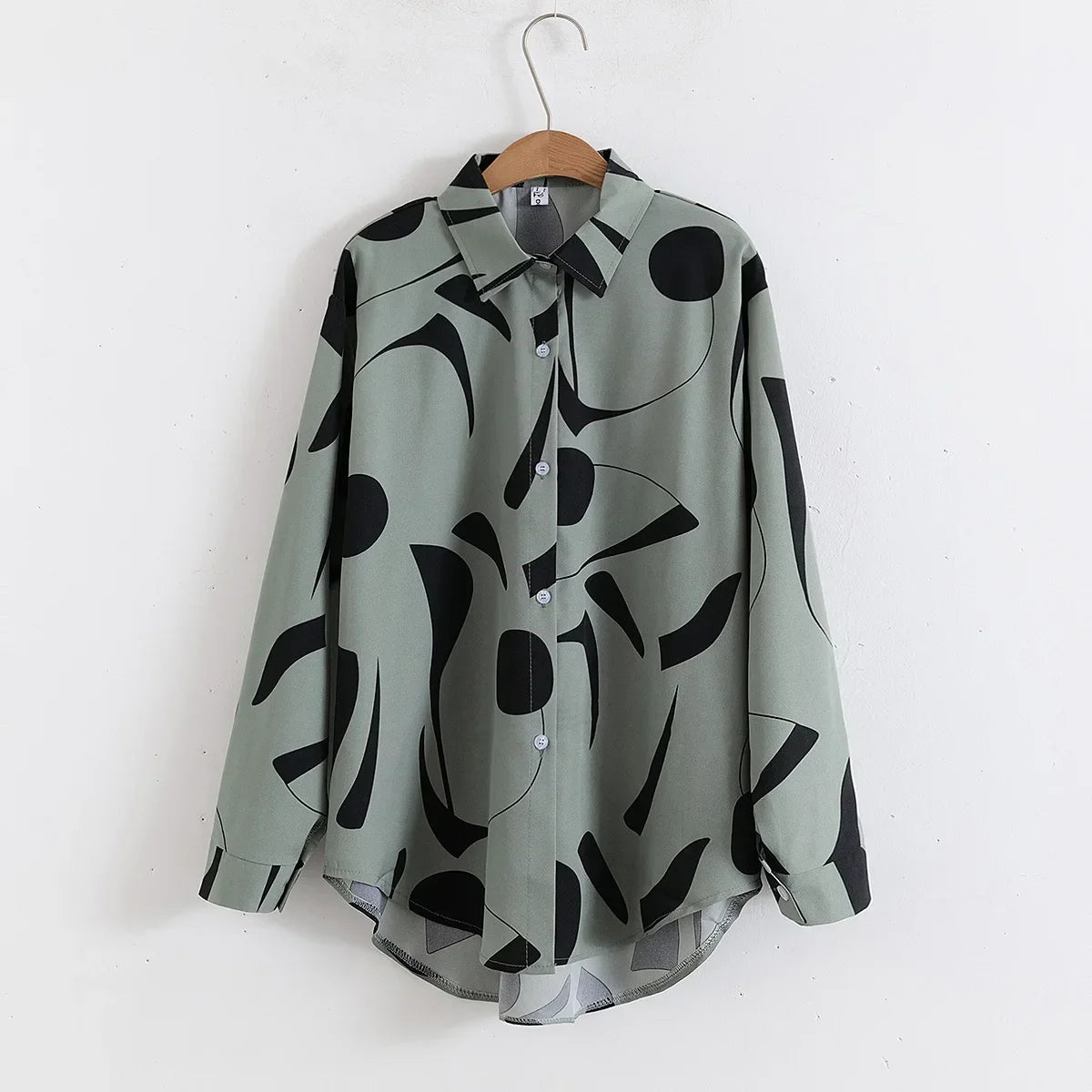 Green shirt with black abstract pattern on a hanger against a white background