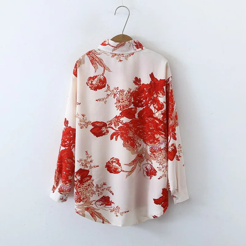 White blouse with red floral pattern on a hanger against a white background