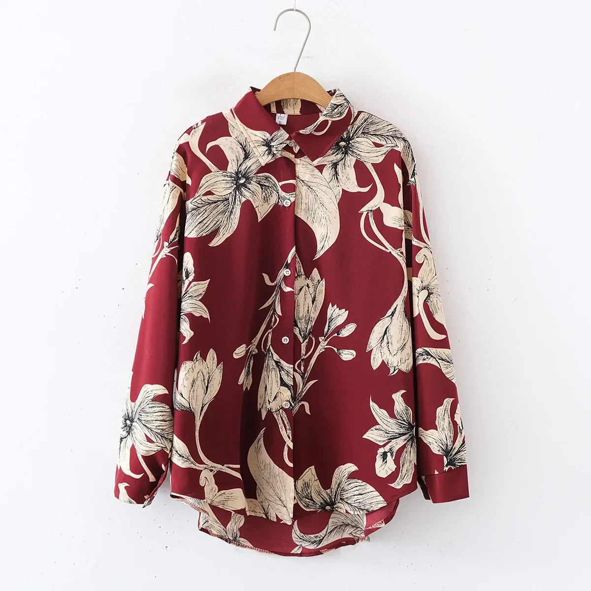 Red floral blouse on a wooden hanger against a white background