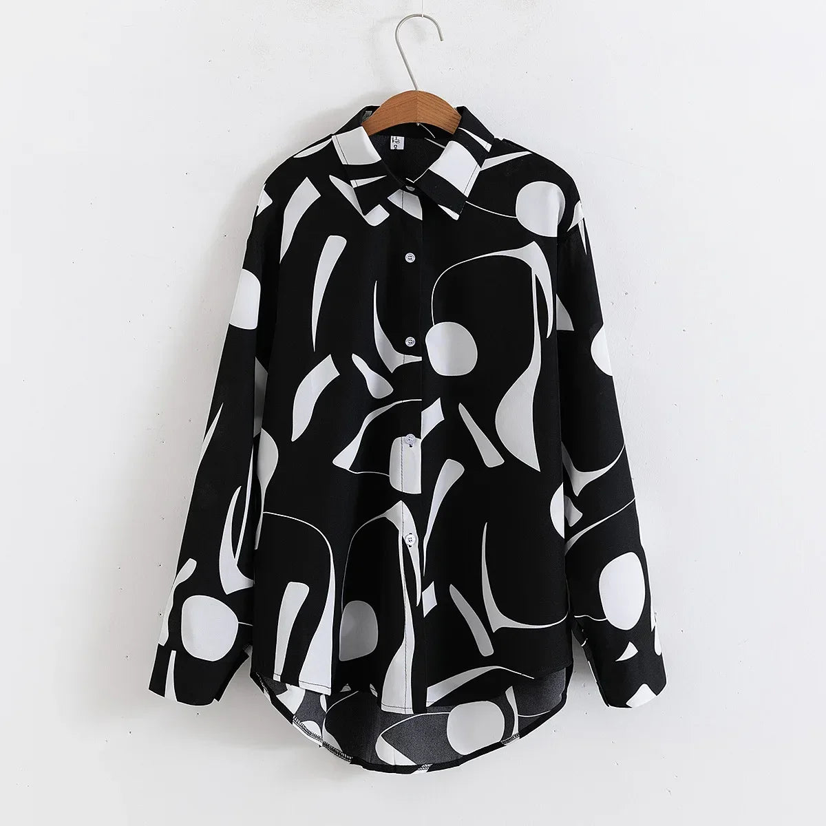 Black and white patterned shirt on a wooden hanger against a white background
