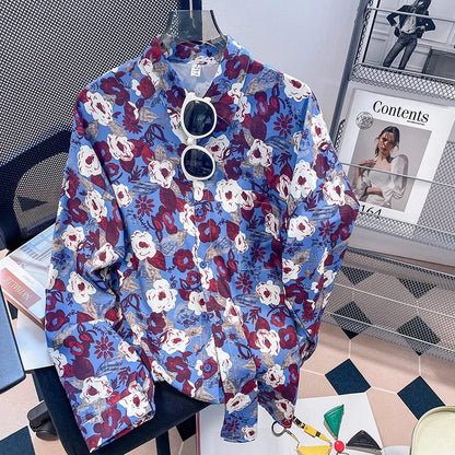 Floral patterned shirt on a hanger with sunglasses, placed on a surface with a magazine in the background.