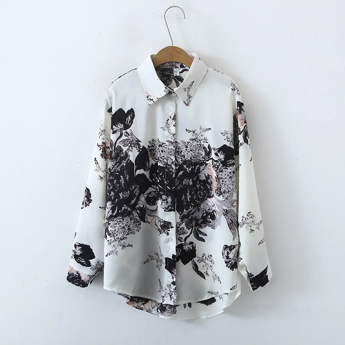 White shirt with black floral pattern on a wooden hanger against a white background