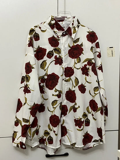 Floral blouse with red roses on a hanger against a white wall
