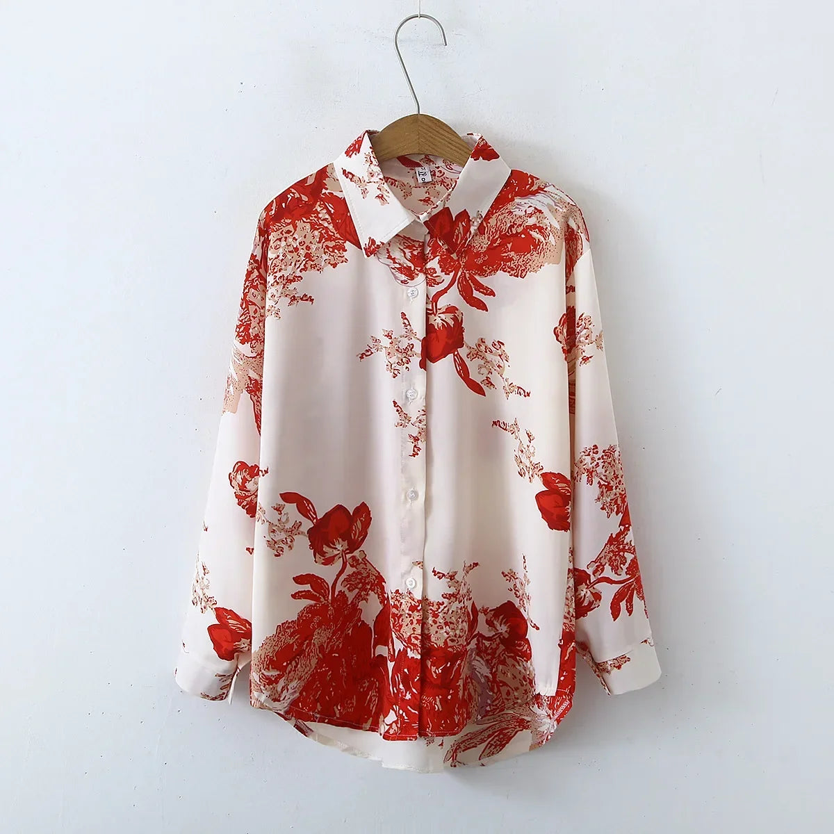 White shirt with red floral pattern on a wooden hanger against a white background