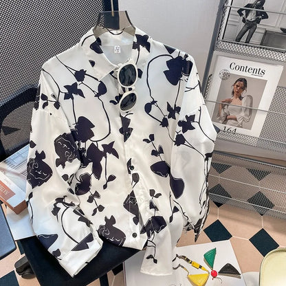 White shirt with black floral pattern on a hanger, with a magazine in the background.