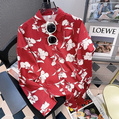 Red floral shirt on a hanger with sunglasses, placed on a magazine with LOEWE branding.