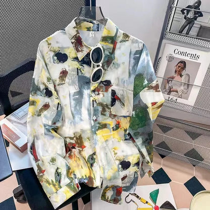 Colorful patterned shirt on a hanger with sunglasses, books, and a magazine in the background.