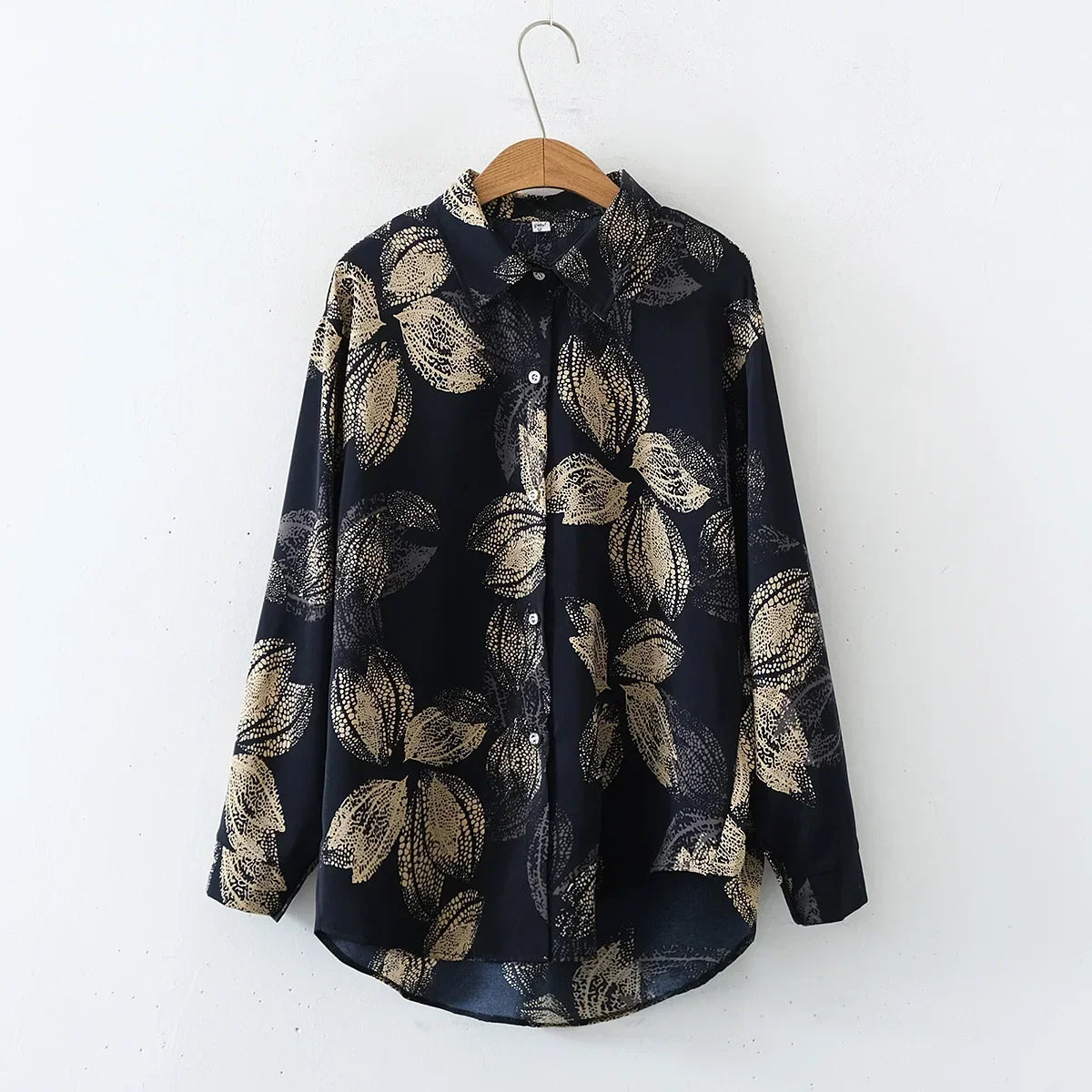 Navy blue shirt with beige leaf pattern on a hanger against a white background