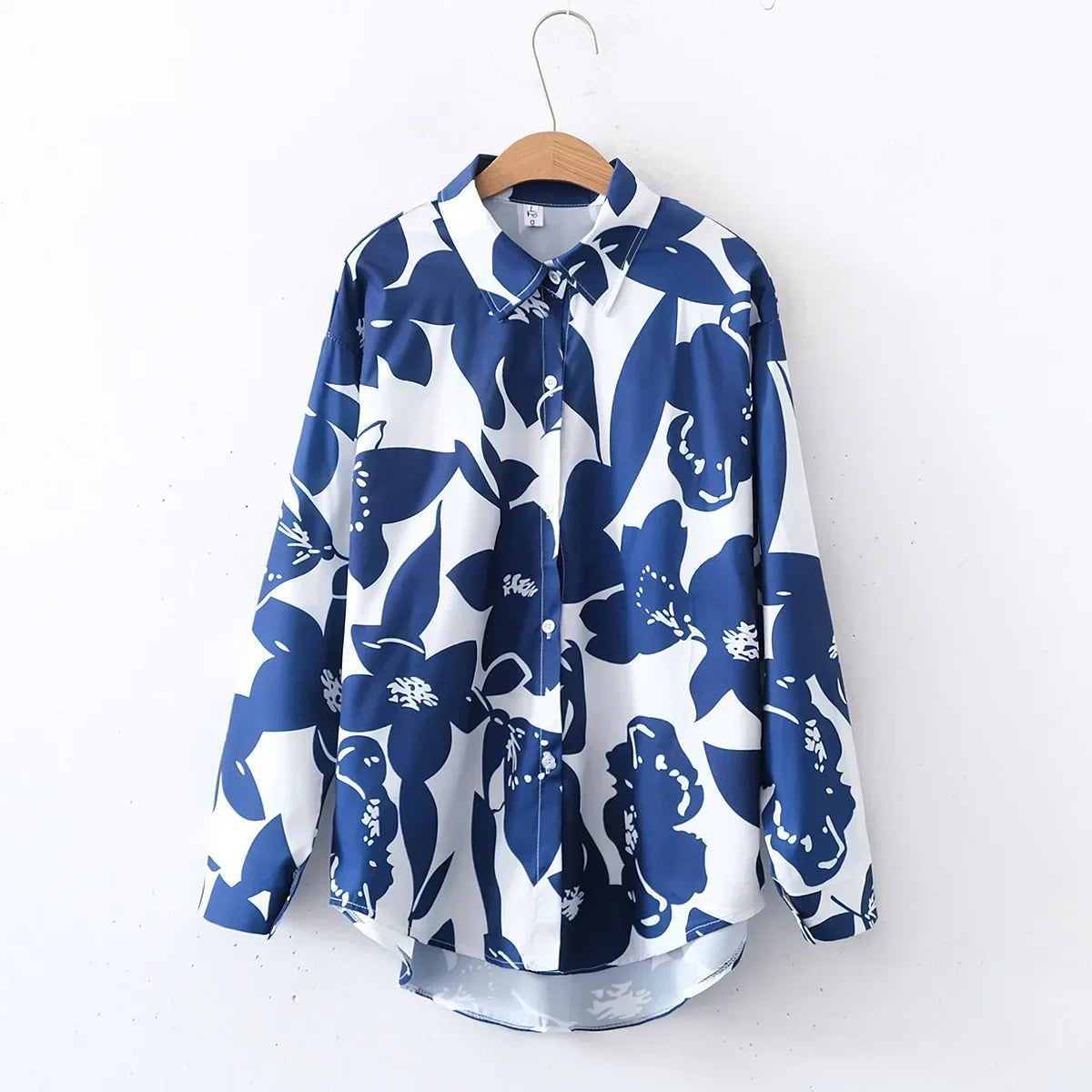 Blue and white floral patterned shirt on a hanger against a white background