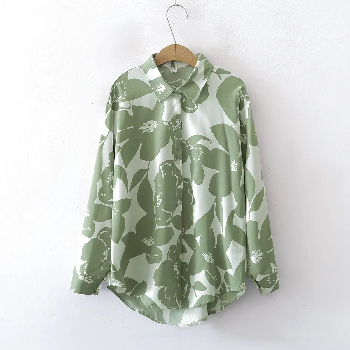 Green floral patterned shirt on a hanger against a white background