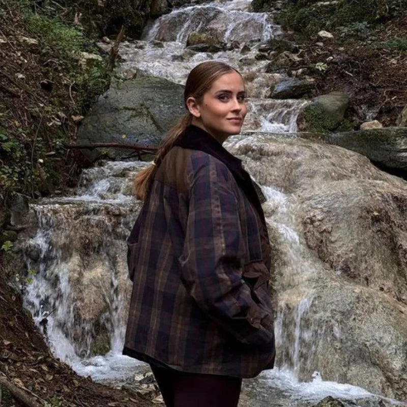 Woman standing in front of a small waterfall in a forest