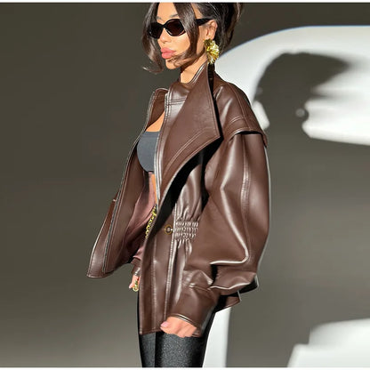 Person wearing a brown leather jacket with a neutral background