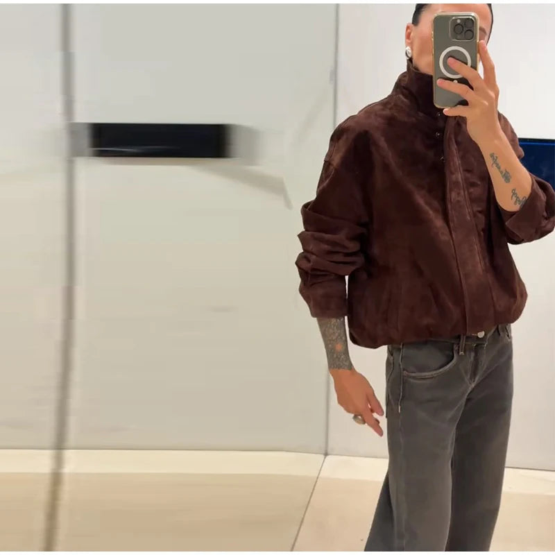 Person wearing a brown jacket and gray pants taking a mirror selfie.