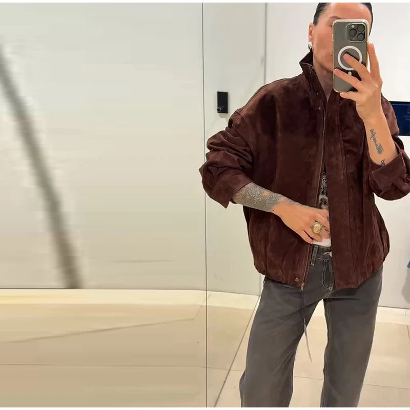 Person wearing a brown jacket taking a mirror selfie.