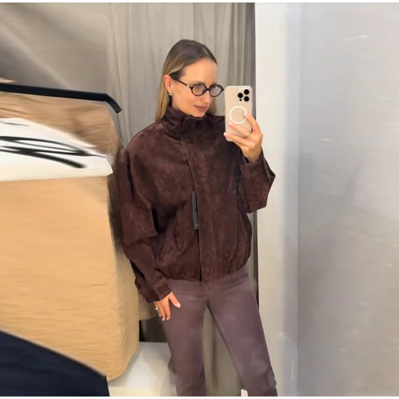 Person wearing a brown jacket and pants taking a mirror selfie.