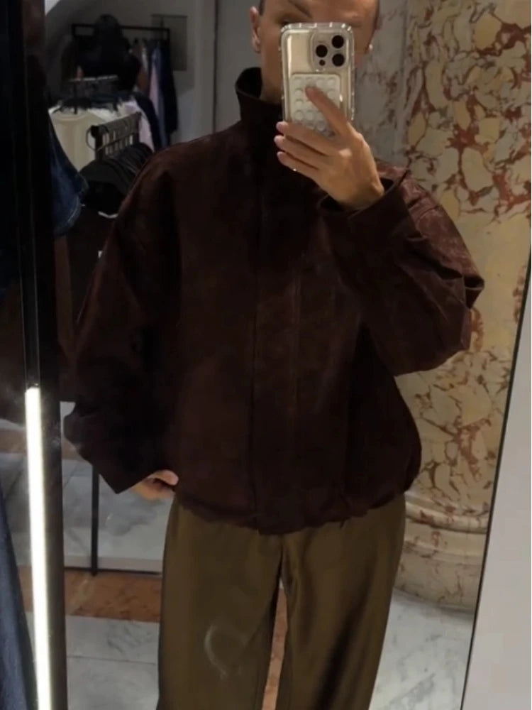 Person wearing a brown jacket and green pants in front of a mirror.