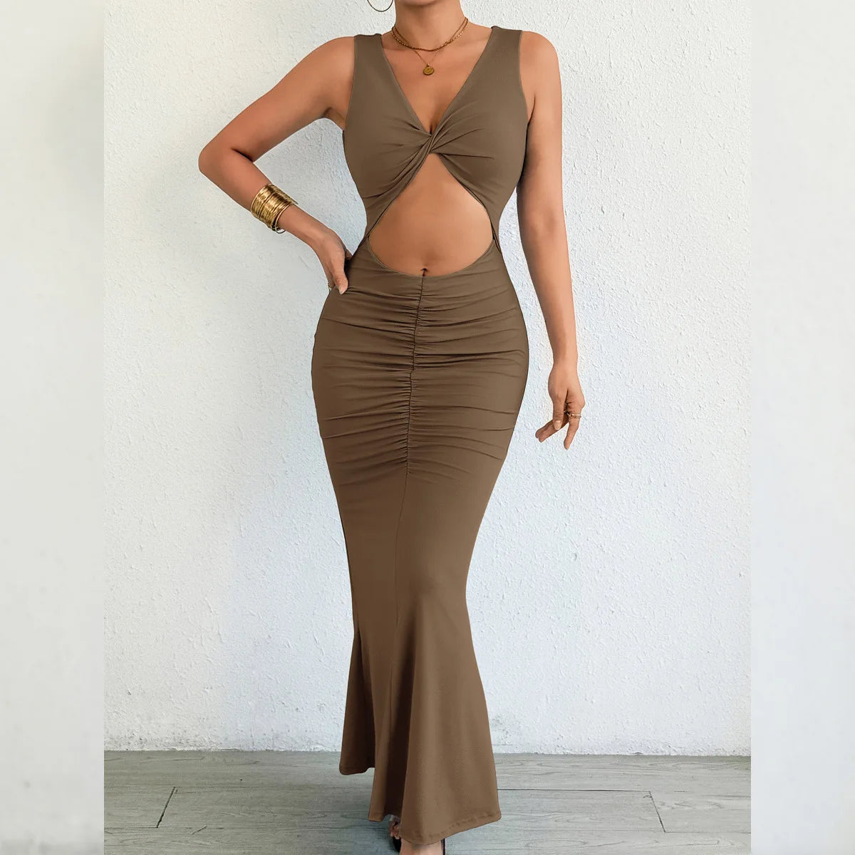 Brown dress with cut-out design worn by a person against a white wall.
