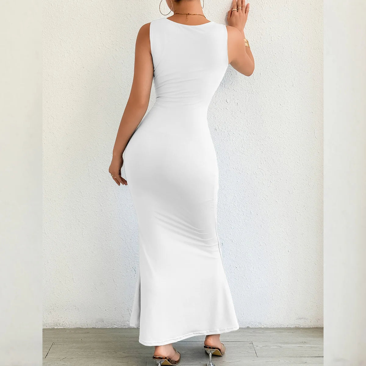 Woman wearing a white sleeveless dress against a plain background