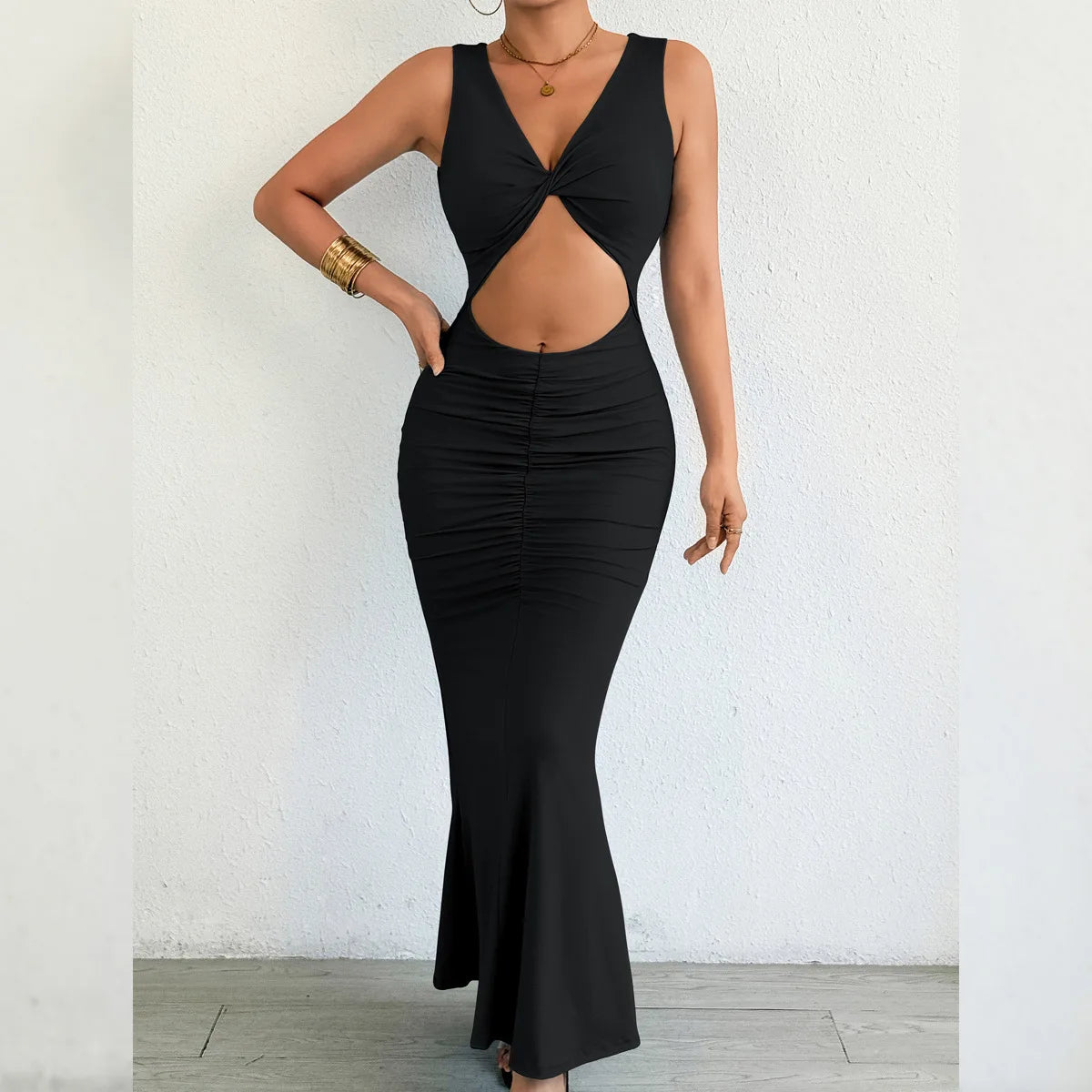 Black dress with cut-out design worn by a person against a white wall.