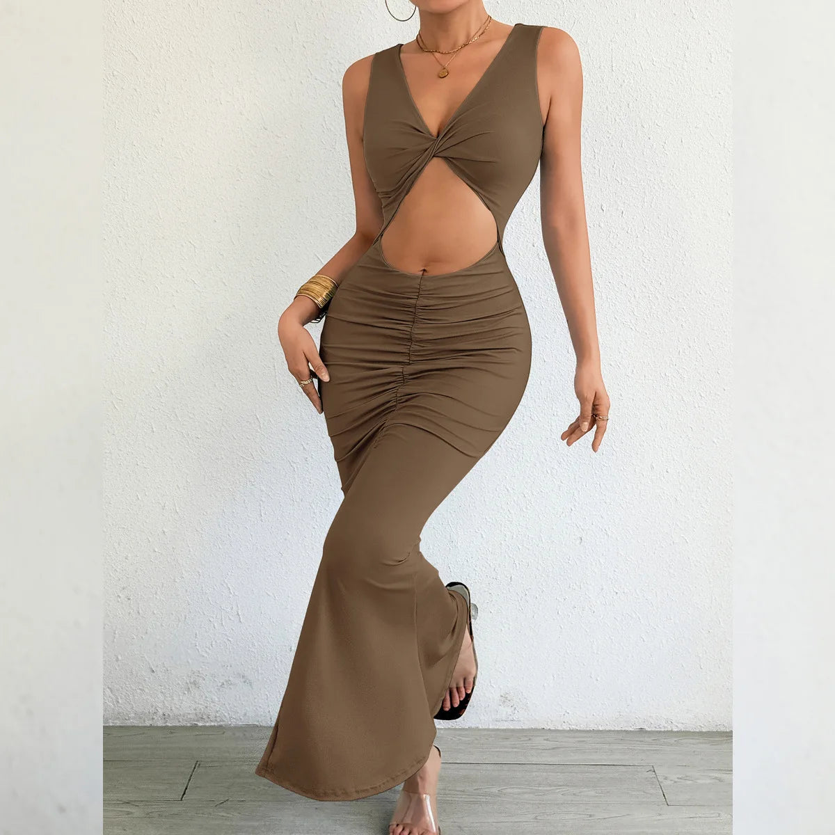 Brown dress with cut-out design worn by a model against a white wall.