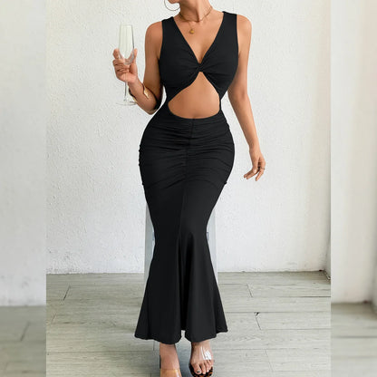 Woman wearing a black dress with cut-out design against a white wall.