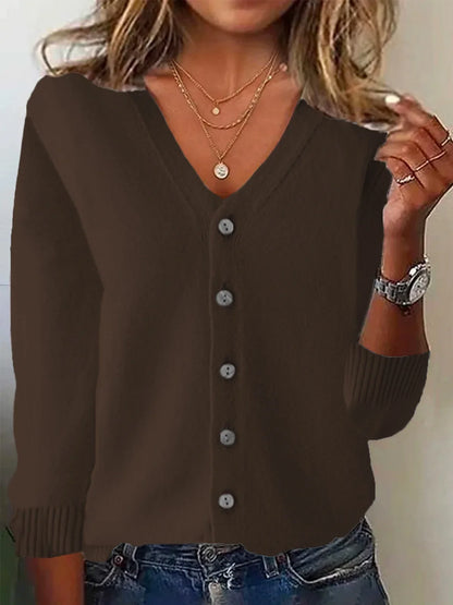 Brown button-up cardigan worn by a person with layered necklaces and a watch.