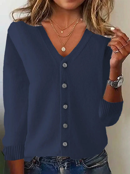 Navy blue cardigan worn by a person with layered necklaces and a watch.