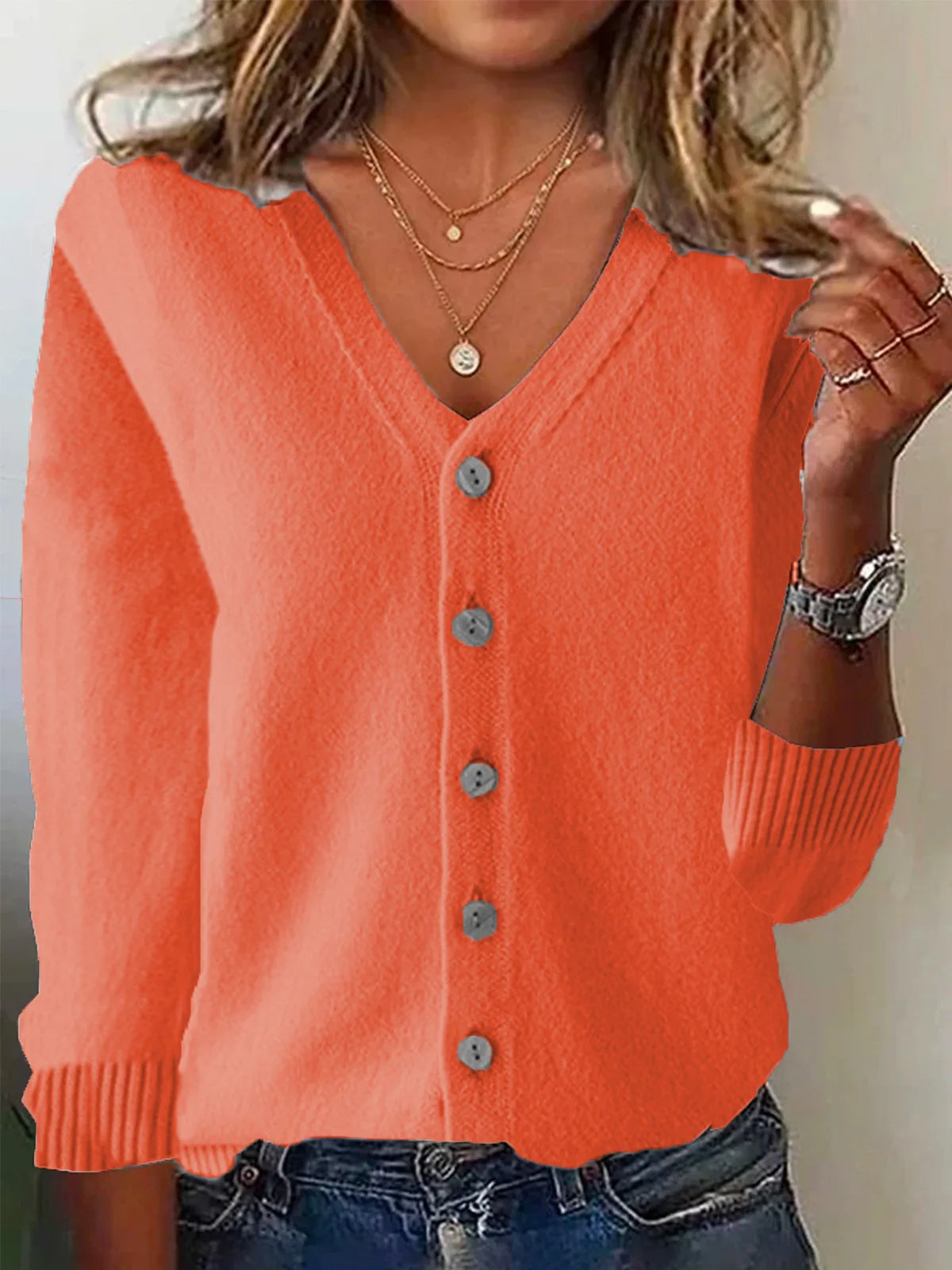 Person wearing an orange cardigan with a neutral background