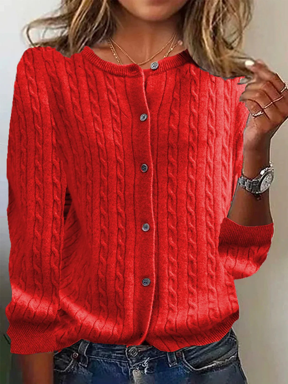 Person wearing a red cable knit sweater with a neutral background