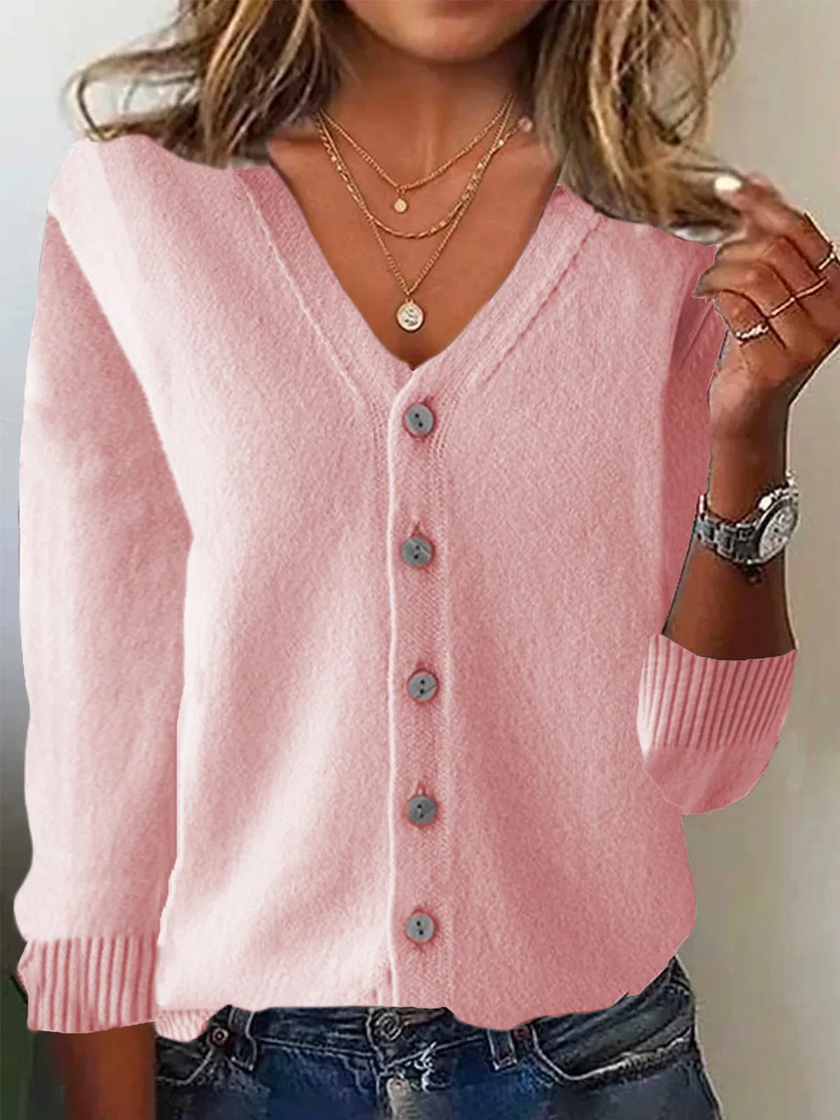 Person wearing a pink cardigan with a neutral background