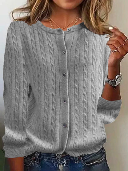 Person wearing a gray cable knit cardigan with a neutral background