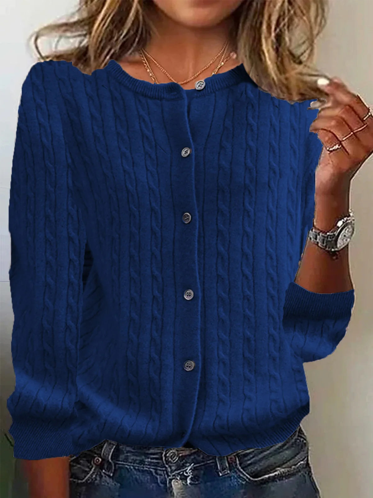 Blue cable knit cardigan worn by a person with a neutral background