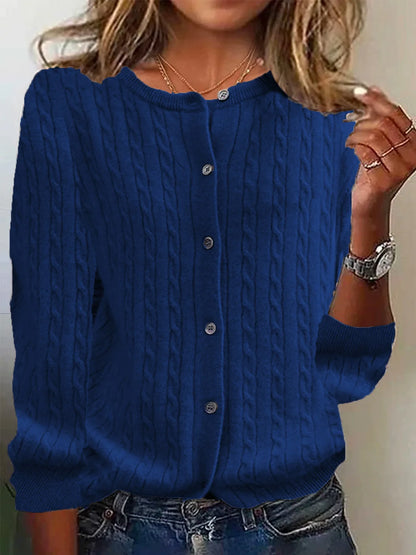 Blue cable knit cardigan worn by a person with a neutral background