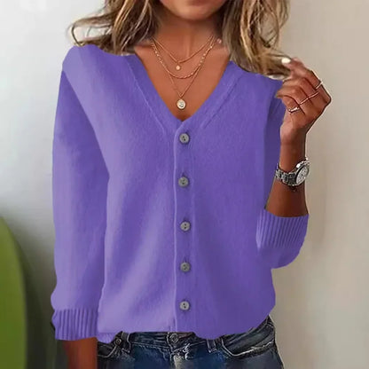 Person wearing a purple cardigan with a neutral background