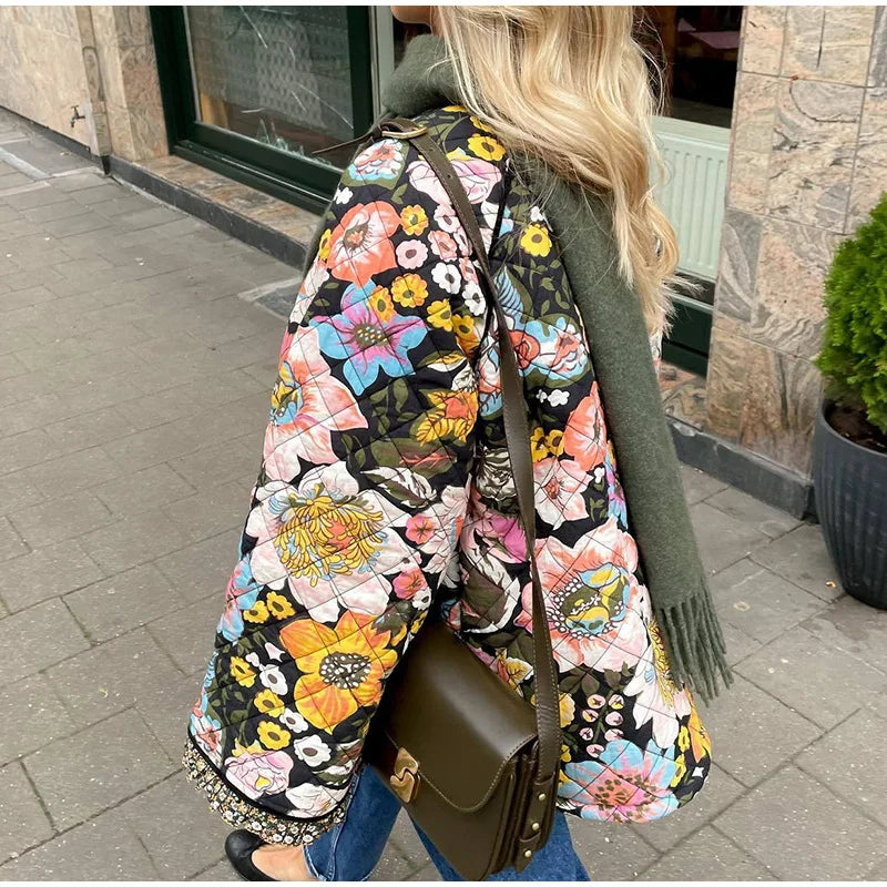 Person wearing a colorful floral backpack and green coat on a sidewalk.
