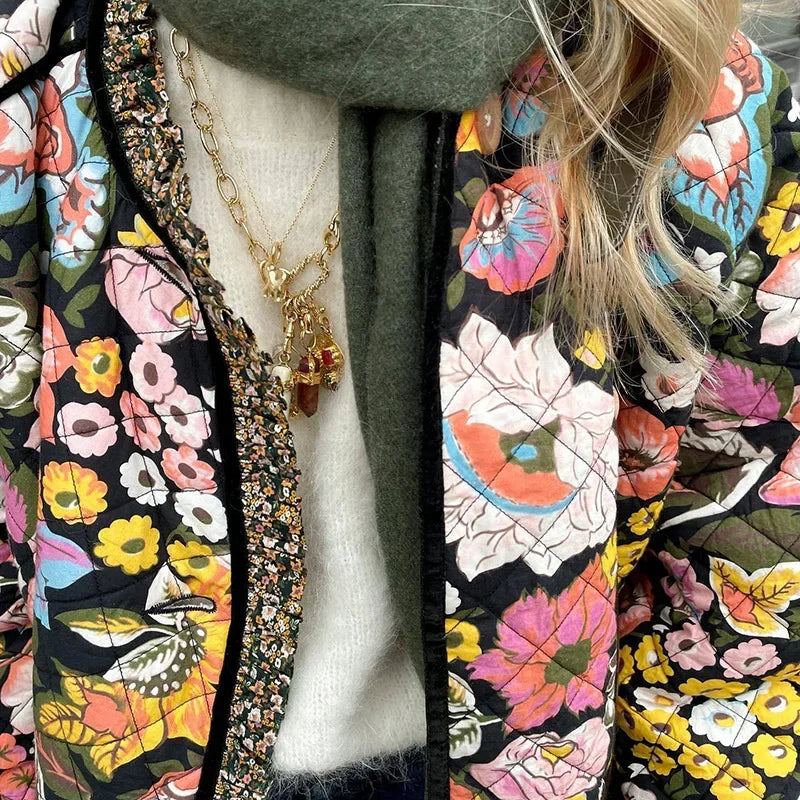 Close-up of a person wearing a colorful floral-patterned coat with a necklace.