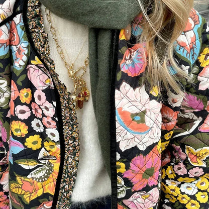 Close-up of a person wearing a colorful floral-patterned coat with a necklace.