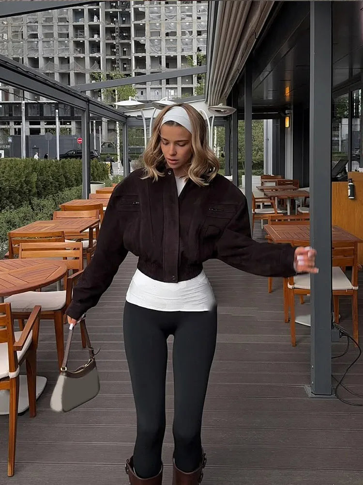 Woman standing in an outdoor cafe setting with tables and chairs.