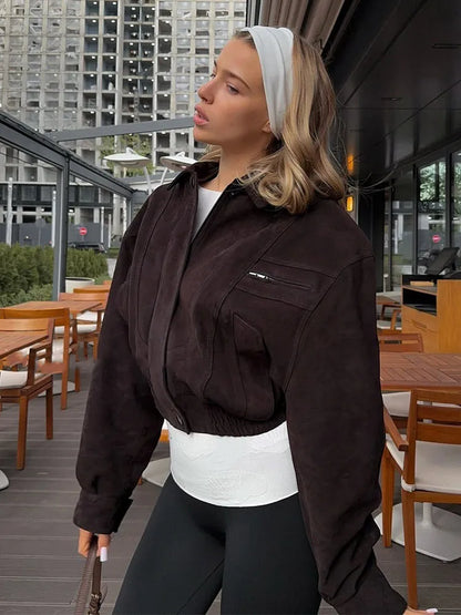 Woman in a brown jacket standing in an outdoor cafe setting