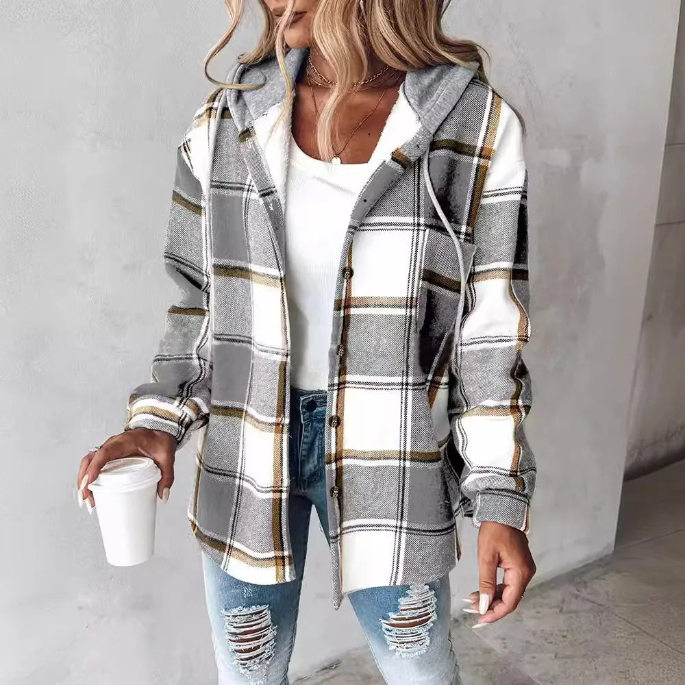Woman wearing a plaid shirt over a white top and ripped jeans, holding a coffee cup.