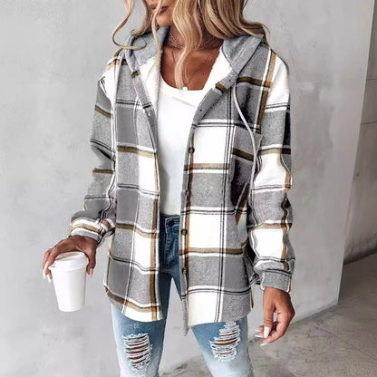 Woman wearing a plaid shirt over a white top and ripped jeans, holding a coffee cup.