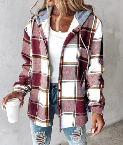 Person wearing a plaid shirt with a hood, holding a coffee cup against a plain background