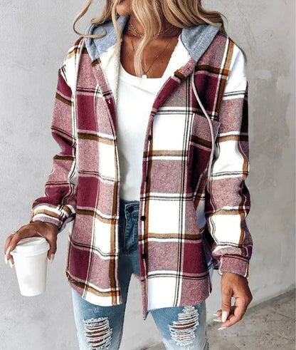 Person wearing a plaid shirt over a white top and jeans, holding a coffee cup.