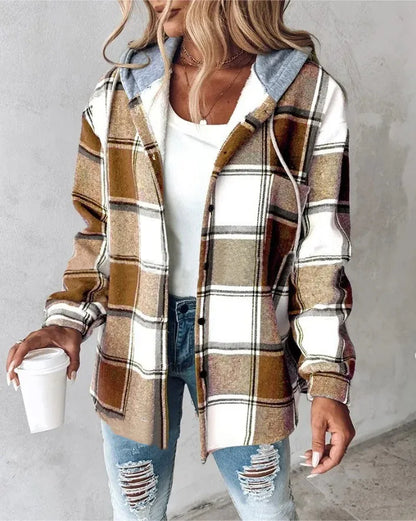 Person wearing a plaid shirt with a hood, holding a coffee cup against a gray background
